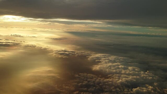 夕日に染まる日没直前の雲上を飛ぶ飛行機からの幻想的な光の風景