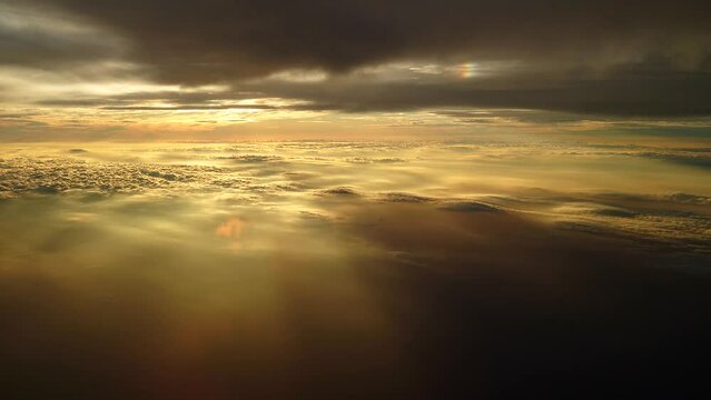 夕日に染まる日没直前の雲上を飛ぶ飛行機からの幻想的な光の風景