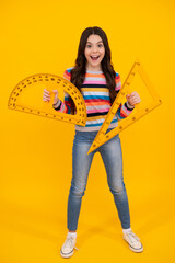 Back to school. School girl hold ruler measuring isolated on yellow background. Happy teenager,...