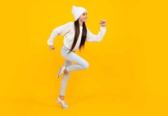 Fototapeta na wymiar Teenager girl jumping. Full length of her she playful preteen teenager girl having fun and jumping isolated on yellow background.