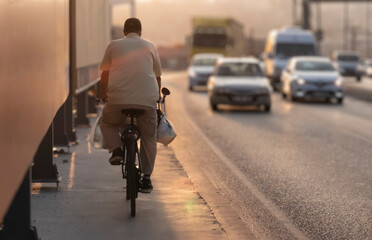 man on bike in city traffic at sunset