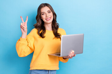 Naklejka premium Photo of young attractive cute pretty gorgeous positive lady hold laptop showing v-sign toothy smile blogger popular isolated on blue color background