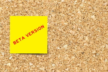 Yellow note paper with word beta version on cork board background with copy space