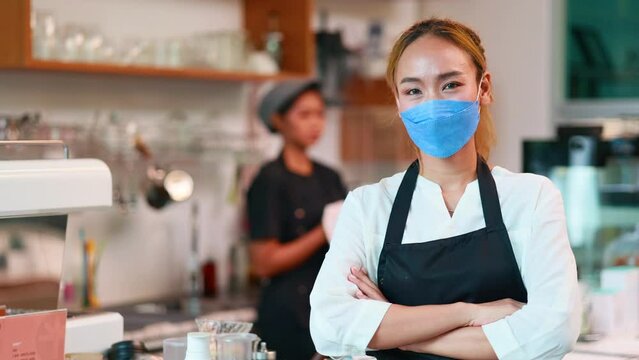 Slow motion VDO. Portrait Asian female owner small business wearing protective face mask at coffee café.