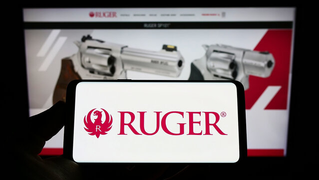 Stuttgart, Germany - 09-14-2022: Person holding mobile phone with logo of American company Sturm, Ruger and Company Inc. on screen in front of web page. Focus on phone display.