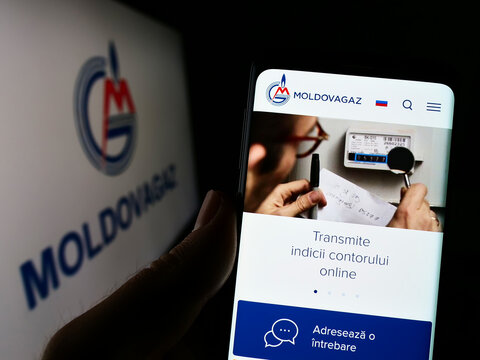 Stuttgart, Germany - 09-14-2022: Person holding cellphnoe with webpage of Moldavian gas company Moldovagaz S.A. on screen in front of logo. Focus on center of phone display.