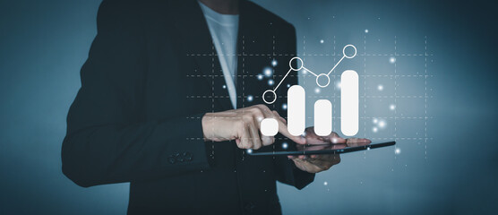 Success business concept. Businessman hand holding tablet with hologram of statistics graph and chart growing graph. Planning and strategy concept.