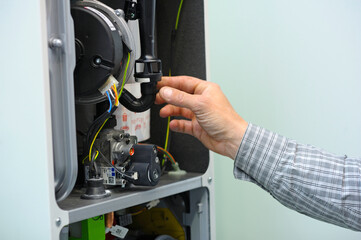 Man hand working with a gas condensing boiler disassembled, parts of section gas condenser - obrazy, fototapety, plakaty