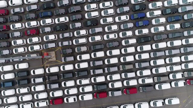 Drones is flying over a lot of cars parked in a automotive factory. new cars lined up for import and export. automobile industry. 4K