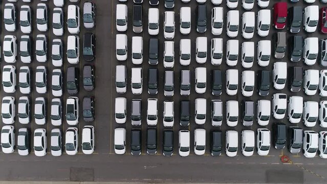 Drones is flying over a lot of cars parked in a automotive factory. new cars lined up for import and export. automobile industry. 4K