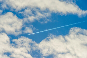 Airplane flying into a blue cloudy sky in bright sunlight in autumn, Almere, Flevoland, The Netherlands, September, 2022