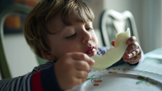 Child eating melon fruit hungry little boy eats healthy snack