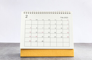 February 2023 Desktop calendar for planners and reminders on a wooden table on a white background. - obrazy, fototapety, plakaty