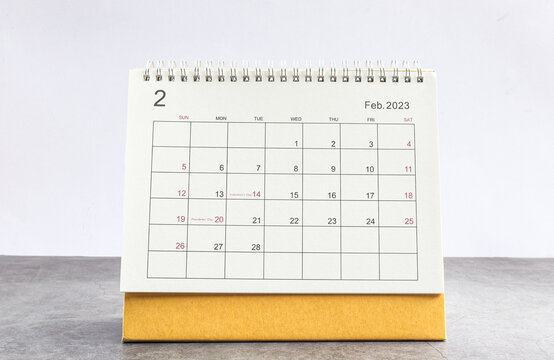 February 2023 Desktop calendar for planners and reminders on a wooden table on a white background.