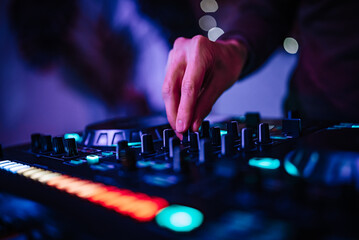 DJ Hands creating and regulating music on dj console mixer in concert nightclub