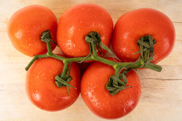 Bunch of tomatoes with water drops on a wooden chopping board 