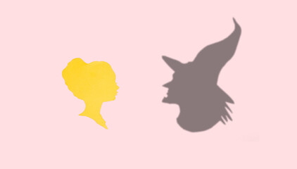 female paper head looking at her witch shadow, creative art halloween concept, pink background, flat lay
