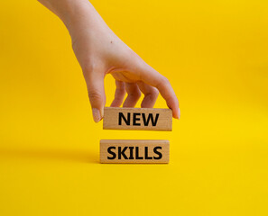 New skills symbol. Wooden blocks with words New skills. Beautiful yellow background. Businessman hand. Business and New skills concept. Copy space.