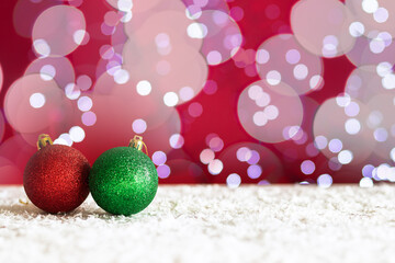 christmas balls on snow on red background with bokeh and lights,new year card with copy space,...
