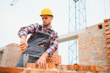 Busy with brick wall. Construction worker in uniform and safety equipment have job on building.