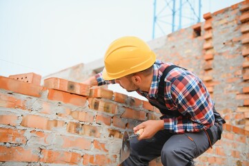 Yellow colored hard hat. Young man working in uniform at construction at daytime.