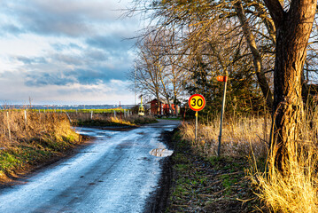 Countryside narrow road by the sea after a winter rain fall. The gloomy sky reflecting in a puddle...