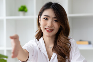 Portrait of charming Asian businesswoman in office looking smiling and shaking hands.