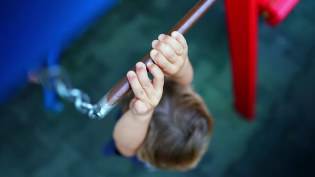 Small boy reaching for monkey bar at playground effortful child holding metal bar