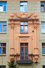 Balconies with columns on facade of old residential building decorated with bas-reliefs. Stalinist architecture, Stalin Empire style. Balcony and windows of soviet building.