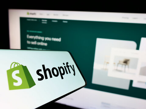 Stuttgart, Germany - 09-18-2022: Mobile phone with logo of Canadian e-commerce company Shopify Inc. on screen in front of business website. Focus on center of phone display.