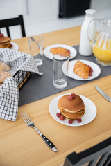 tasty pancakes near baked croissants and jug with orange juice on table.