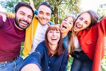 Happy caucasian friends taking selfie picture outside - Group of young people having fun smiling at camera together - Friendship concept with guys and girls hanging out on a sunny day