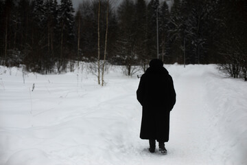 Woman walks through park in winter. Pensioner walks in winter.