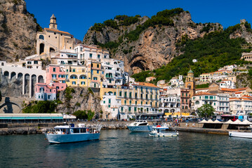 Fototapeta na wymiar Amalfi harbour on the famous Amalfi Coast in Campania Italy. Picturesque historic village panorama with colorful houses. Summer atmosphere in popular holiday destination seen from a tourist vessel.