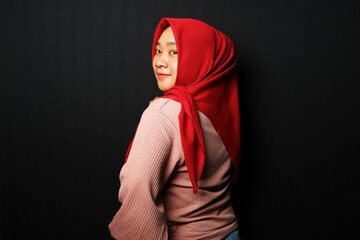 Hijab woman posing with right hand on the chin isolated on black background.