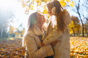 Young Mother and daughter walking in the park and enjoying the beautiful autumn nature. Rest, childhood, walk, family.