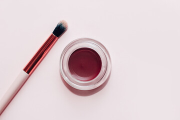 A jar with eyeshadow and eyebrow pomade on a white background.