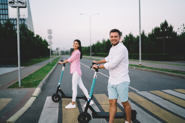 Happy couple with kick scooters on road