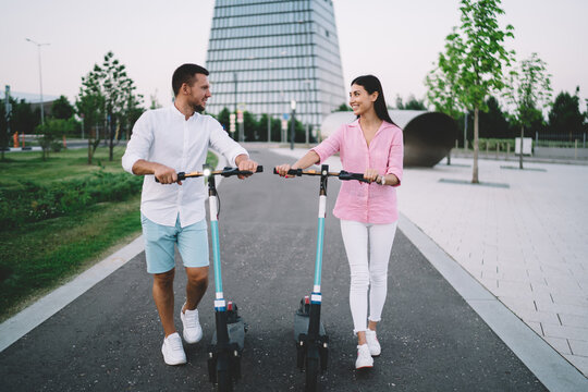 Loving man and woman with kick scooters on road