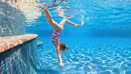 Funny portrait of child learning swimming, dive in blue pool with fun - jumping deep down...