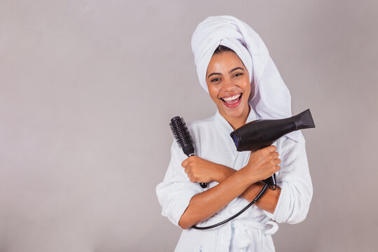 Beautiful Brazilian Black Woman, Wearing Bathrobe And Towel. Holding Hairdryer And Brush, Beauty Salon, Spa, Aesthetics Concept.