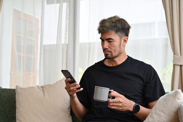 Portrait of Young Man with Facial Hair using smartphone at home.