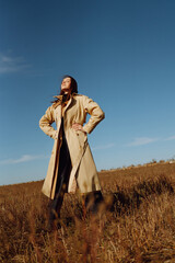 Young woman in stylish clothes posing in the autumn field. Nature, fashion, vacation and lifestyle. Travel and adventure.