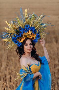 A beautiful young woman in a dress in the color of the national flag of Ukraine is standing in a wheat field. The concept of independence of Ukraine.
