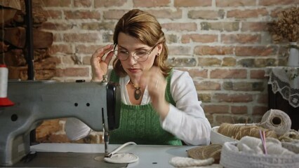 A smart adult woman at home sews a mat with a sewing machine for a gift