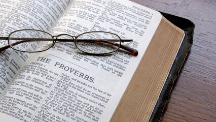 An old King James Bible on a table open to the book of Proverbs. - obrazy, fototapety, plakaty