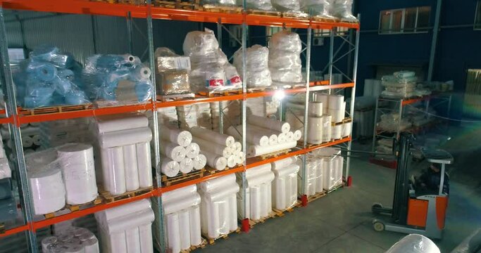 The forklift puts the goods on the shelf of the warehouse. The forklift puts the nonwovens on the shelf of the factory warehouse. Warehouse at the nonwovens factory.