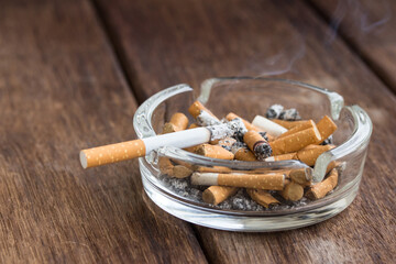  Many cigarette stubs and ash in a glass ashtray