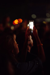 Using a smartphone in a public event, live music festival. Technologies, party, lifestyle.