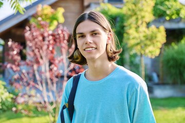 Outdoor portrait of teenage guy with backpack looking at camera